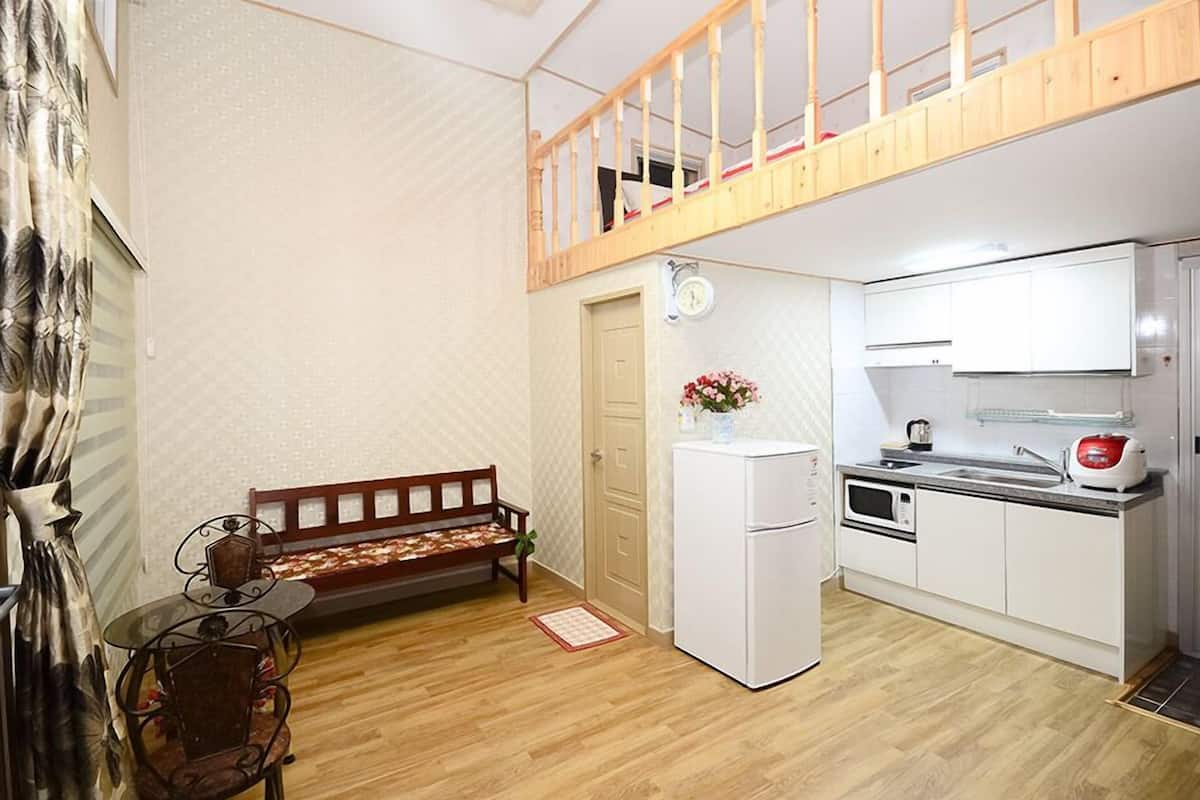 A compact kitchen with a wooden bench, a refrigerator, and a microwave.