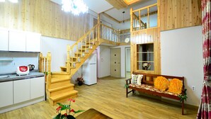 A spacious kitchen with wooden cabinets, a built-in stove, and a wooden staircase leading to an upper level. - Sun and Moon Pension (Yeosu)