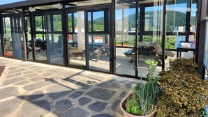A modern building with large glass windows, outdoor seating, and a stone-paved area. - Sun and Moon Pension (Yeosu)