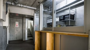 Uma cozinha comercial com eletrodomésticos de aço inoxidável, balcão de madeira e estrutura de vidro.