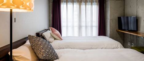 A hotel room with two beds, a TV, and an air conditioning unit.