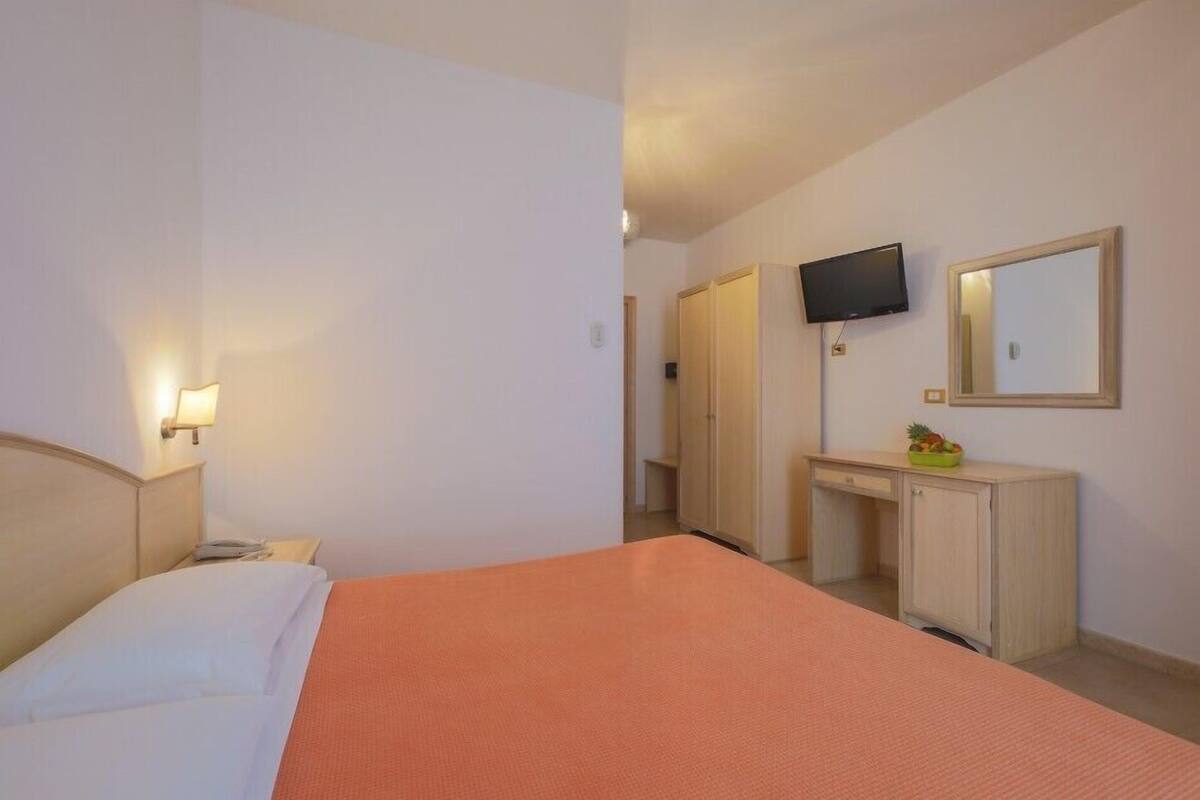 A hotel room with a bed, a desk, a television, and a mirror.