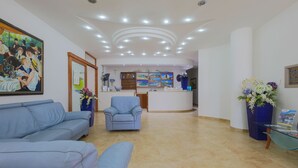 Un hall d’hôtel comprenant un comptoir d’accueil, un espace salon et des œuvres d’art accrochées aux murs.