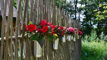 A wooden fence with metal containers holding red flowers.