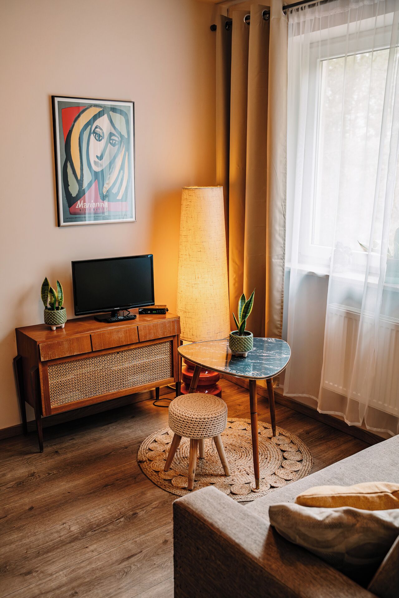 Ein gemütliches Zimmer mit einem Holzkasten, einem Fernseher, einer Lampe und einem kleinen Tisch mit Pflanzen.
