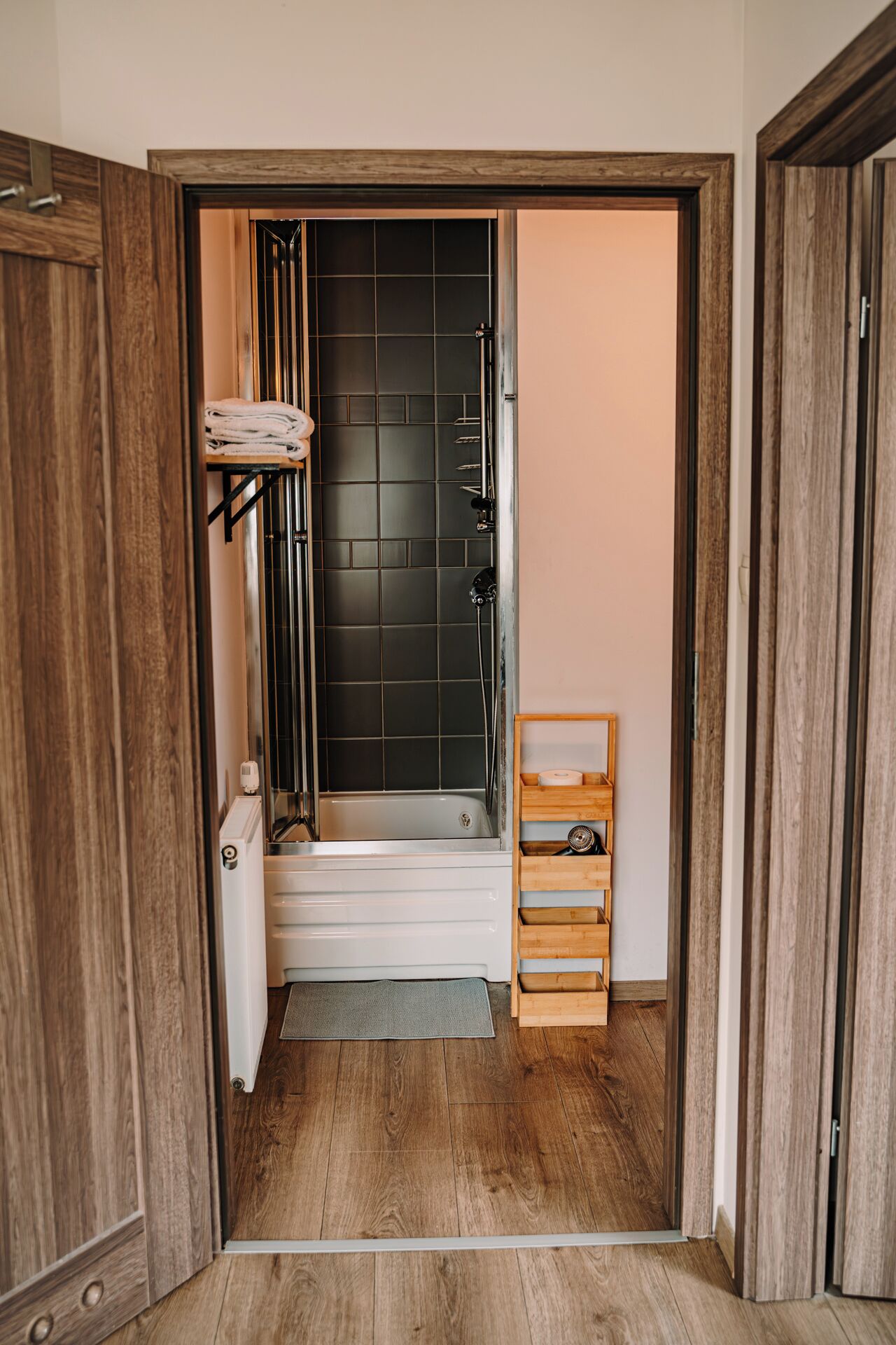A bathroom with a bathtub, a towel rack, and a wooden shelf.