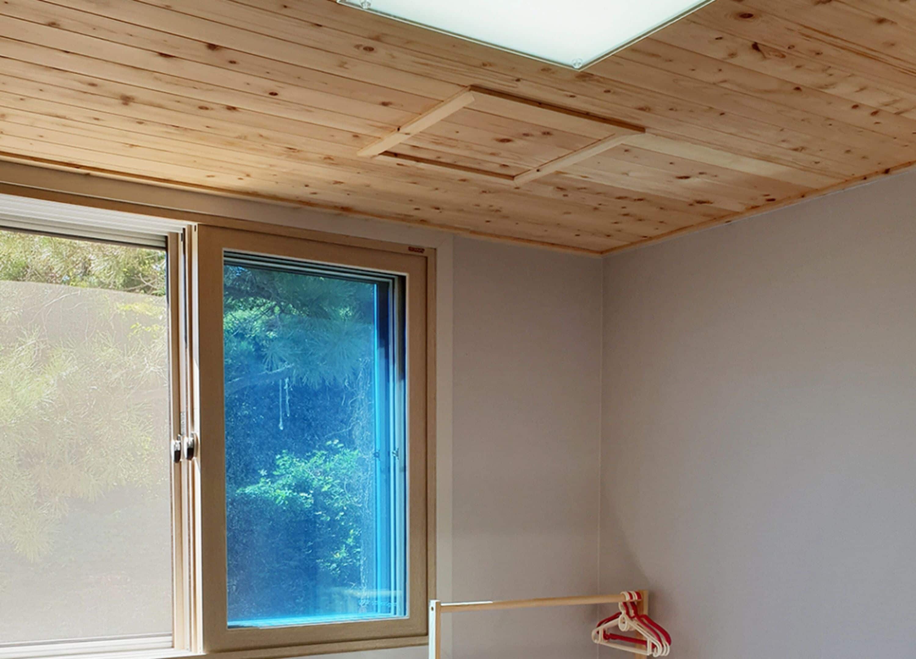 Una habitación con un gran ventanal, techo de madera y una puerta visible.
