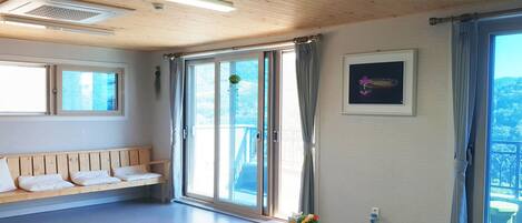 Una habitación con un banco de madera, una mesa y un amplio ventanal con cortinas.
