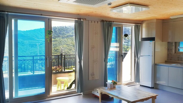 Eine moderne Küche mit Einbaukühlschrank, einem Esstisch und Blick auf einen Balkon mit Tisch und Stühlen.