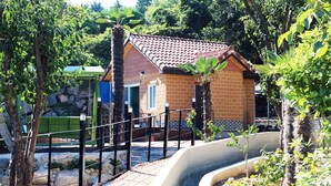 Ein Backsteinhaus mit Ziegeldach, umgeben von Grünpflanzen und einer Betonwassereinrichtung.