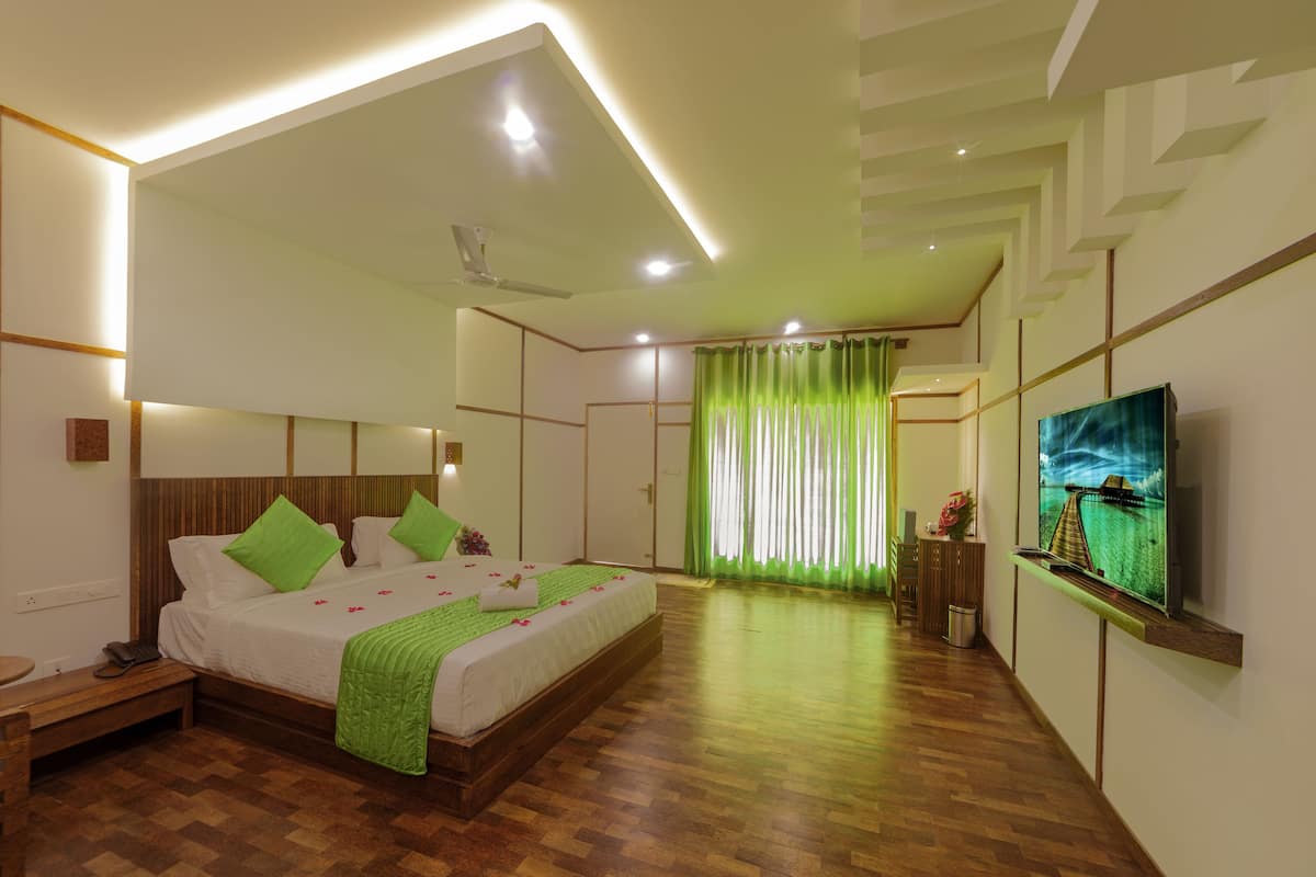 A modern hotel room with a large bed, a television, and a wooden floor.