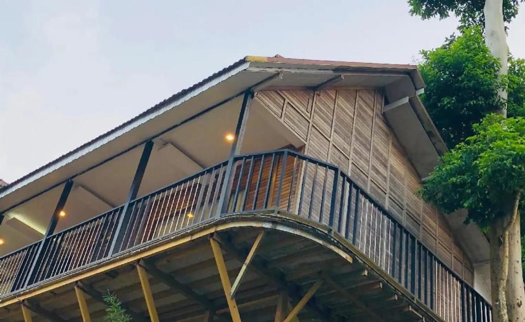 A building with a balcony, wooden exterior, and a metal railing.