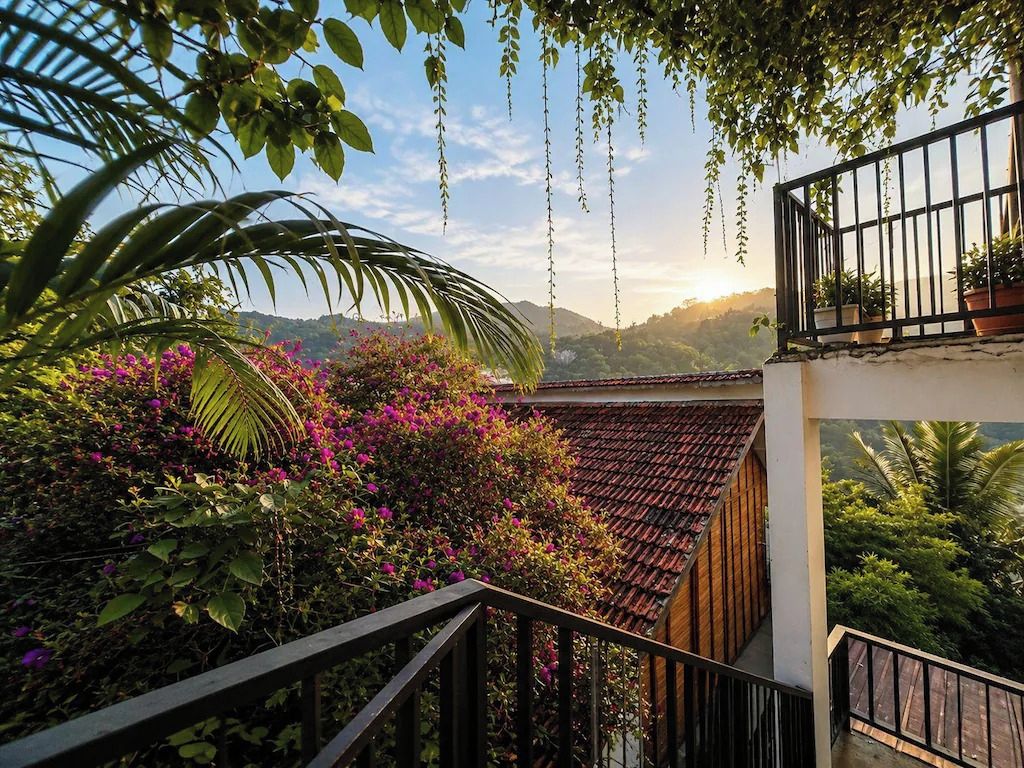 A balcony with a view of a mountainous landscape, surrounded by lush greenery and flowering plants.