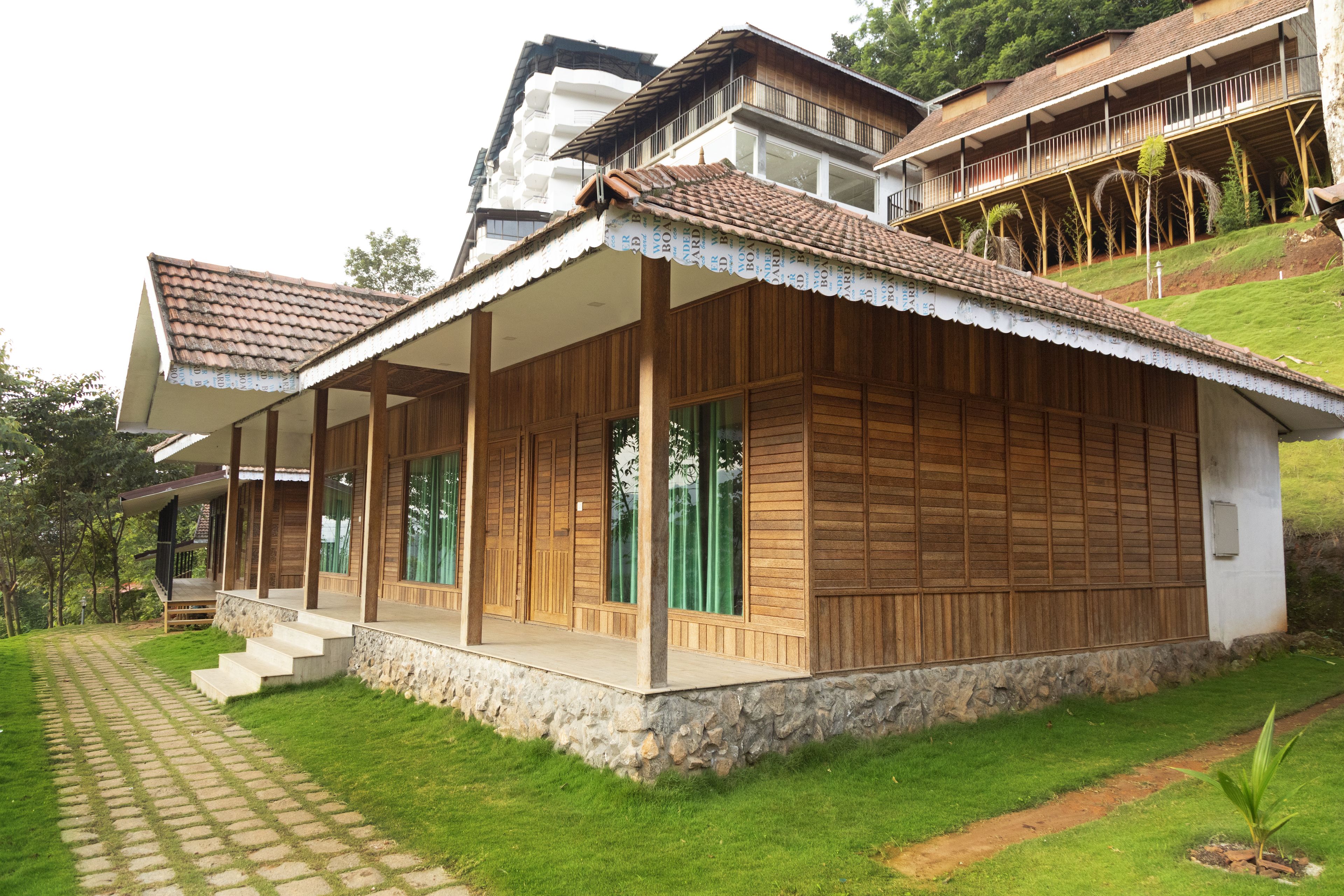 A two-story wooden house with a covered porch and a stone foundation.