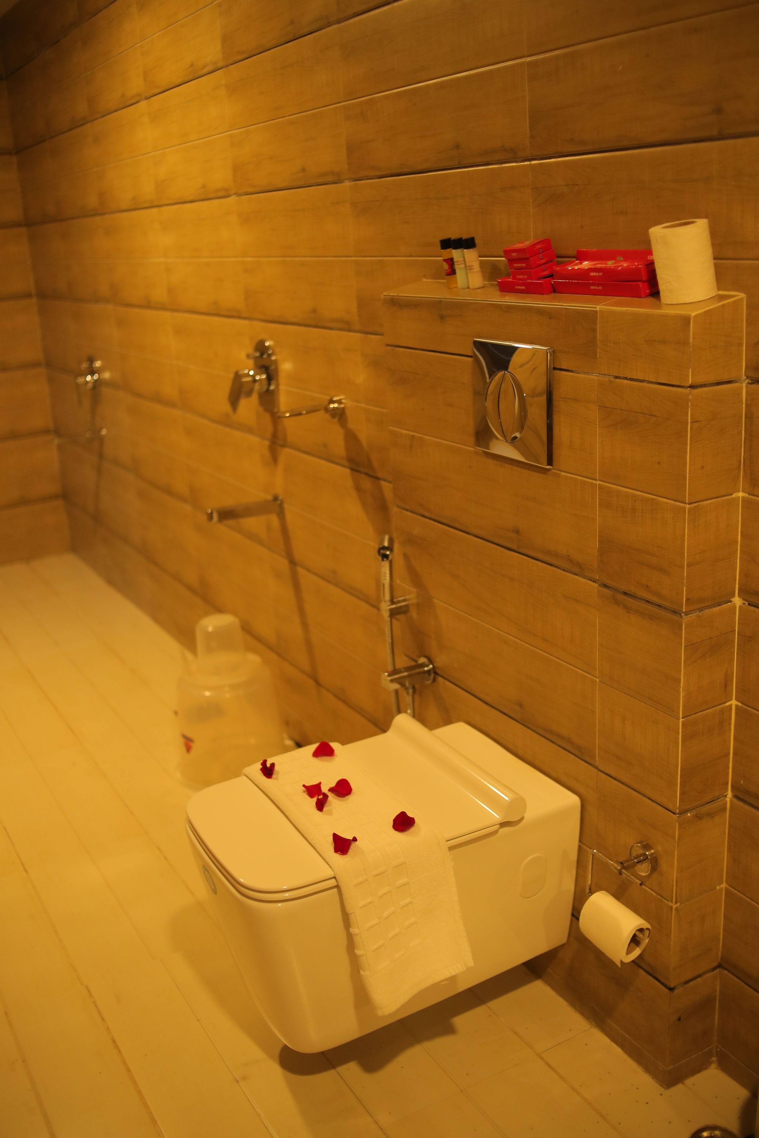 A bathroom with wooden walls, a white toilet, a shower, and a towel rack.