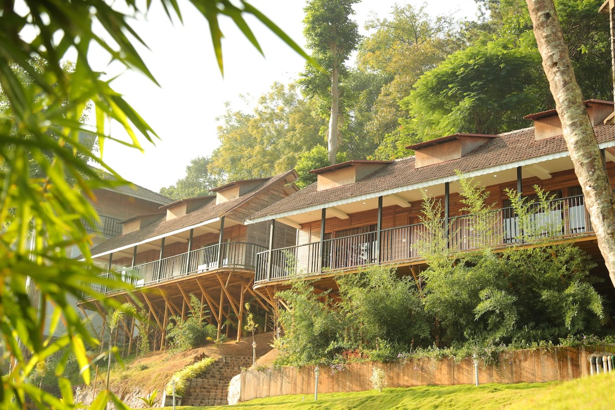 A multi-story hotel with balconies, surrounded by lush greenery and trees.