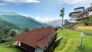 A traditional house with a red roof, surrounded by lush green hills and a clear sky. - Dream Coconut Villa Resort (Devikolam)