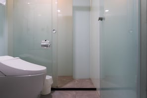 A modern bathroom with a glass shower enclosure, a toilet, and a small trash bin. - V Hotel (Taipei)