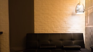 Un sofá de cuero negro frente a una pared de ladrillo blanco, con un aplique decorativo encima.