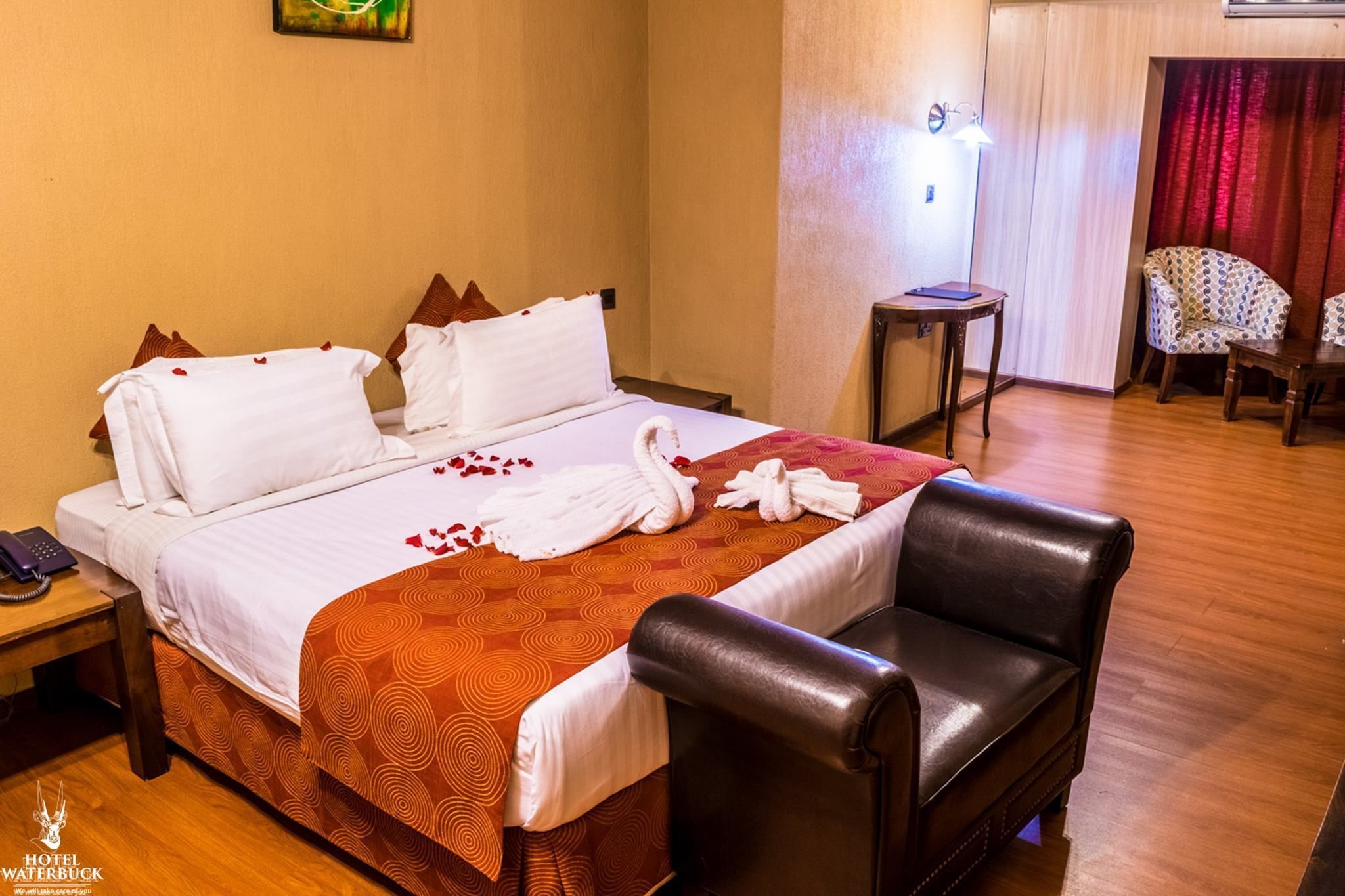 Quarto de hotel com uma cama, uma cadeira, uma mesa pequena e um abajur.