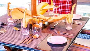 Una mesa lista para comer con mantel a cuadros, cristalería transparente y cubiertos ordenados.