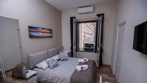 Camera da letto ordinata con un letto, comodini, un quadro e una finestra vista edifici.