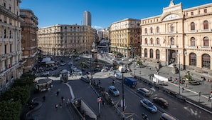 Un'affollata intersezione cittadina con edifici storici, un tram e una statua.