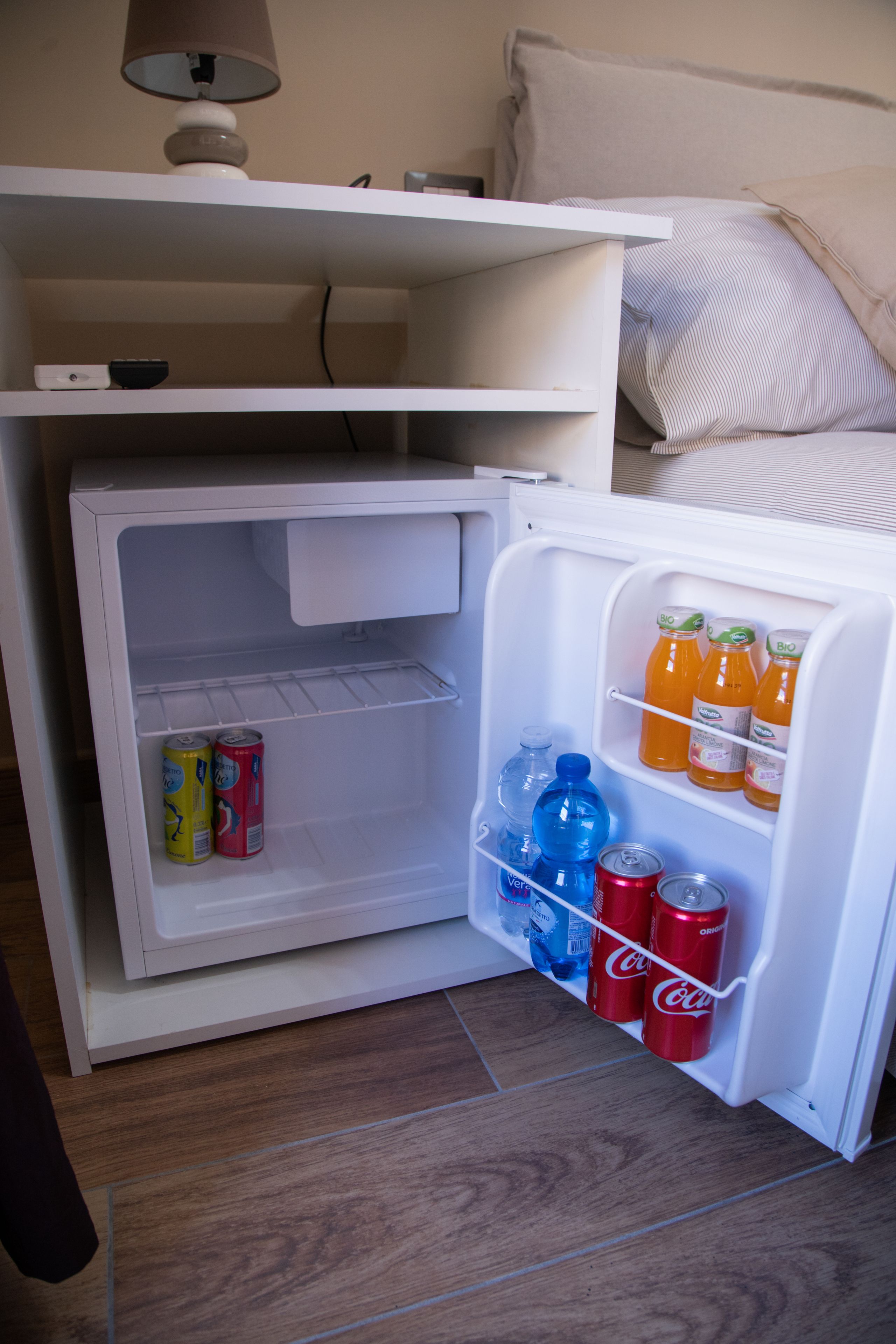 Ein kleiner Kühlschrank mit einer Ablage und einem Türfach für Getränke und Dosen.