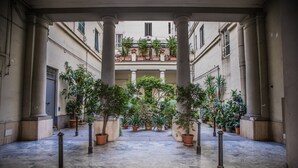Un cortile con colonne, piante in vaso e pavimento piastrellato.