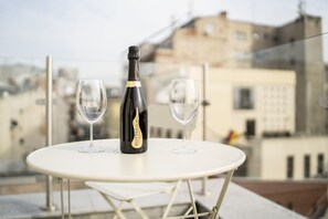 A bottle of Bottega wine on a white table with two empty glasses, set against a cityscape view. - New Era Hotel Bucharest City (Bucharest)