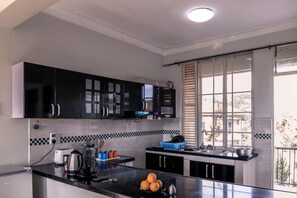 Een koelkast, een kookplaat, kookgerei, borden en bestek