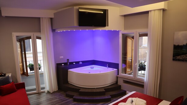 A modern hotel room with a large bed, a built-in jacuzzi, and a TV mounted on the wall. - Millina Suites In Navona (Rome)