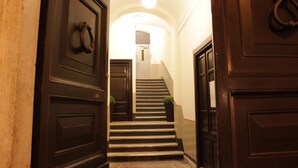 A staircase with dark wooden doors and a light fixture at the top. - Millina Suites In Navona (Rome)