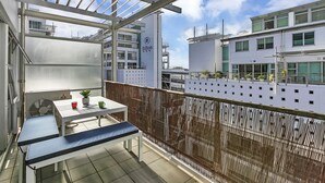 Ein Balkon mit Tisch, Stühlen und einer Topfpflanze.