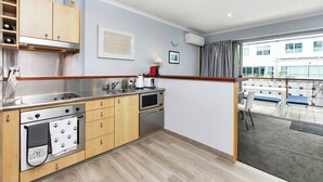Eine moderne Küche mit Edelstahlgeräten, Holzschränken und Blick auf einen Balkon mit Sitzgelegenheit.