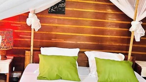 Una cama con ropa de cama blanca y verde, un cabecero de madera y un dosel.