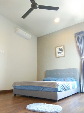 A bedroom with a bed, a ceiling fan, an air conditioning unit, a framed picture on the wall, and a window with curtains.