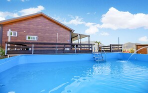 A swimming pool with a wooden deck and a building in the background.