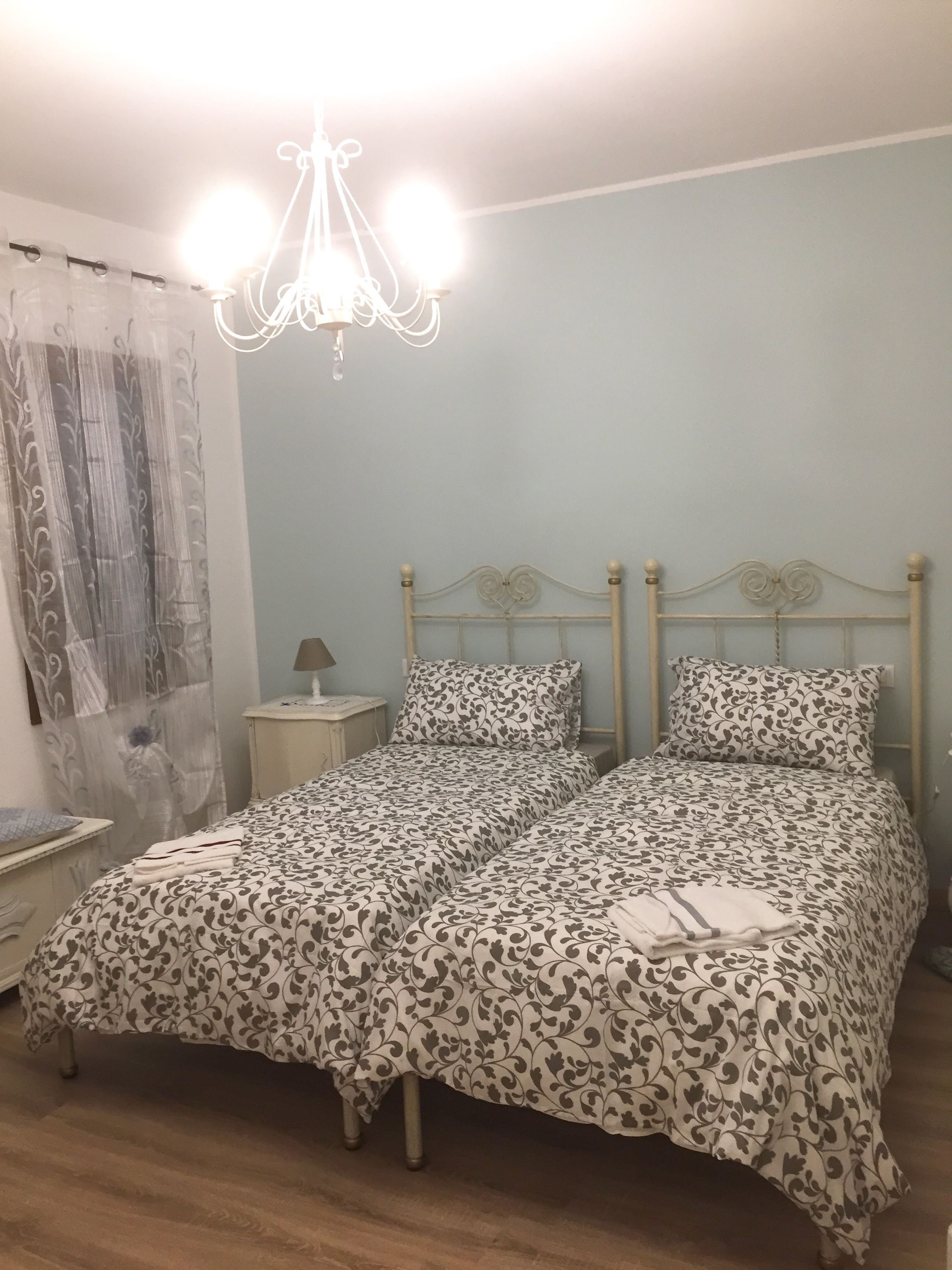 A bedroom with a double bed, a nightstand, a lamp, and a chandelier.