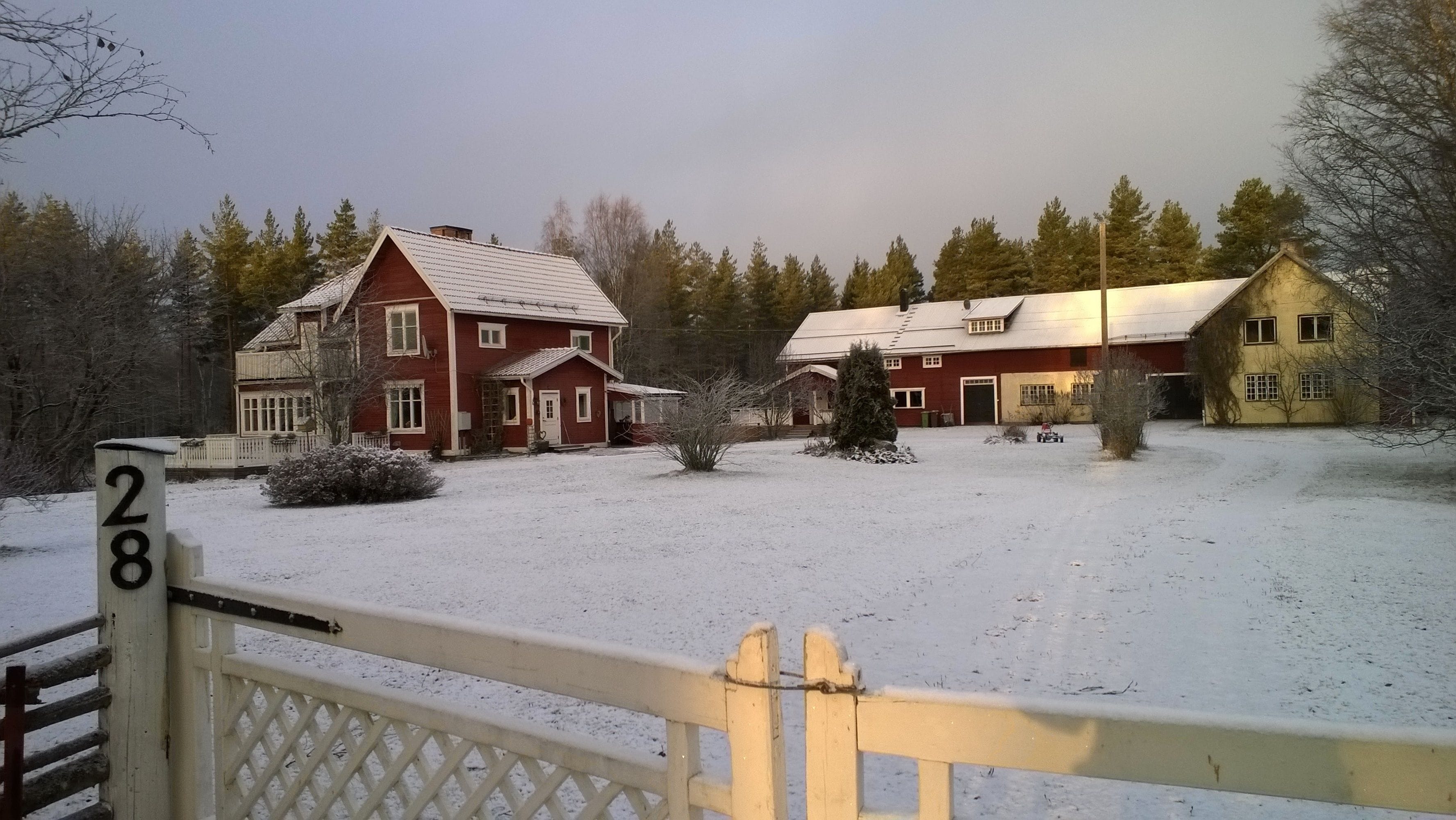 A snow-covered property with a red house, a yellow house, and a number 28 sign.