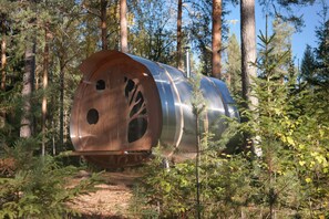 A cylindrical metal structure in a forest. - Näsets Marcusgård (Furudal)