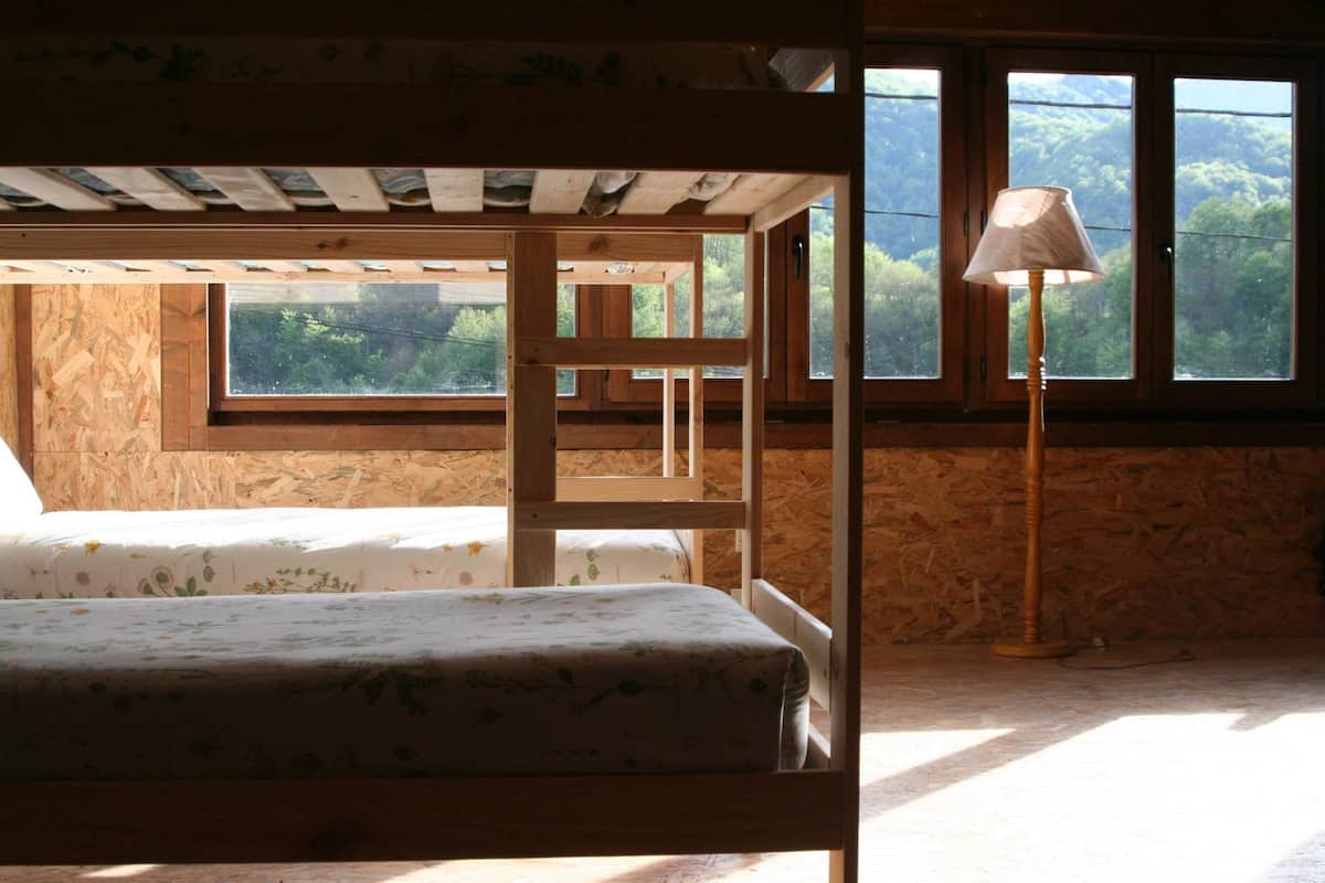 Habitación con literas de madera, ventana y lámpara.