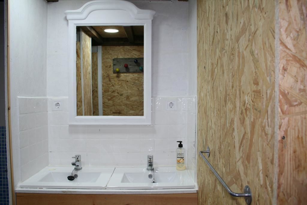 A bathroom with two sinks, a mirror, and a wooden wall.