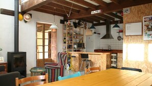 Une cuisine rustique avec des poutres en bois, un poêle et un coin repas comprenant une table et des chaises en bois.