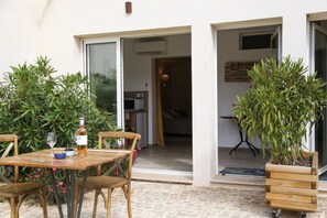 Een terras buiten met een houten tafel, stoelen en een potplant.
