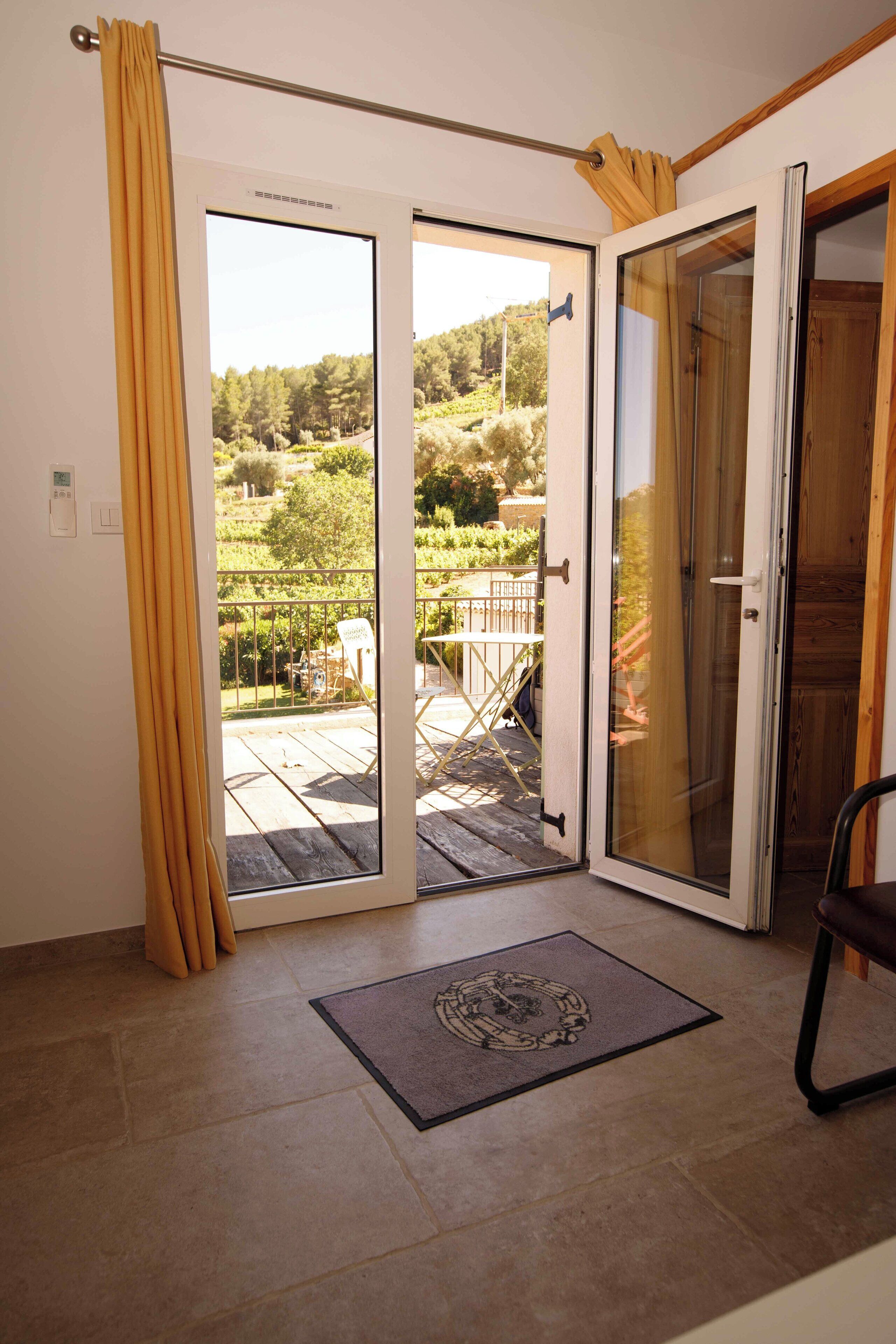 Une pièce dotée d’une porte-fenêtre coulissante donnant sur un balcon avec vue sur un jardin.