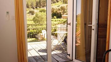 Une pièce dotée d’une porte-fenêtre coulissante donnant sur un balcon avec vue sur un jardin.