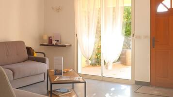 Una sala de estar con sofá, una mesa de centro y un ventanal corredizo que da a un espacio exterior.