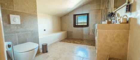 A bathroom with a bathtub, toilet, and shower area.