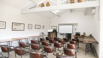 Une salle de conférence avec une longue table, des fauteuils en cuir marron, un tableau blanc et des tableaux encadrés accrochés aux murs.